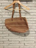 Front view of vintage woven bag showing woven body and leather straps.