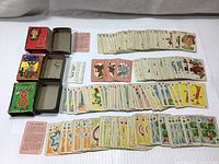 Image showing all four Whitman vintage mini card decks and their cards spread out next to their boxes.