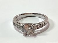 Close-up front view showing round solid Swarovski crystal center on rhodium plated band with pave crystals channel set along band shoulders.