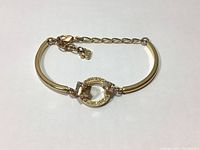 Front view of genuine Swarovski gold tone geometric bangle with crystal centerpiece and lobster clasp with adjustable chain.