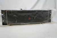 Front and top angled view of the Bogen HTA125A amplifier wrapped in plastic, showing front panel details including switches and indicators.