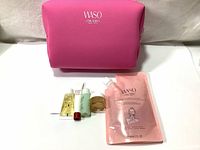 Photo showing full set including pink pouch, 90ml cleanser pouch, and five additional travel-sized skincare products.