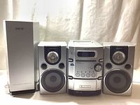 Photo showing Sony micro Hi-Fi stereo system with main unit, two bookshelf speakers, and extra bass reflex subwoofer in silver color.