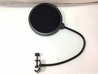 Close-up image of the black circular pop filter windscreen showing the mesh screen and clamp mechanism on adjustable gooseneck.