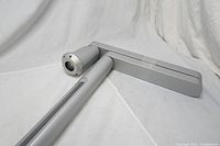 Full view of silver-colored video camera on a silver adjustable extension arm lying on a white surface.