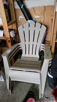 Set of three beige plastic Muskoka lawn chairs stacked together showing slatted design and wide armrests.