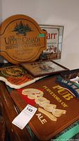View showing multiple wooden and framed plaques on furniture including Upper Canada Brewing Company wooden plaque and framed Old Parr mirror plaque