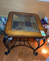 Side view of the side table showing metal legs and part of the wooden frame with slate tile top