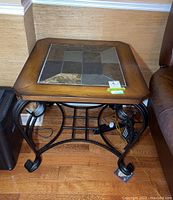 Full view of the side table showing wooden frame with slate tile inlay and curved metal legs with scroll detailing.