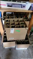 Photo showing five cardboard cases filled with empty green wine bottles, subdivided by cardboard dividers.