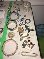 Full view of all bracelets, brooches, and pendant on white surface with green tape line.