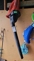 Black & Decker electric leaf blower hanging on a pegboard, showing the full length including the nozzle and handle.