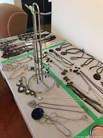 Wide view of necklace tree stand with multiple necklaces arranged around on a table.