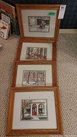Four wood framed prints arranged vertically on the floor showing different architectural and interior scenes.