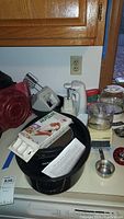 Overview of black turkey pan with cookbooks and kitchen appliances on countertop