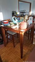 Bar height table with various ceramic and glass items placed on top, showing overall look and height compared to stools.