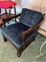 Front and side view of the armchair showing wood frame and blue button-tufted upholstery