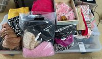 Overview of assorted fabrics, linens, wool sweaters, and scarves in various colors and patterns, some items bagged and boxed