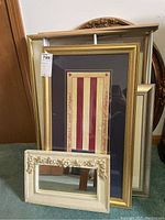 Cluster of framed American flag art pieces and rectangular mirrors with ornate frames showing sizes and frame details.