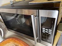 Full view of the Black & Decker microwave oven showing the stainless steel handle, black front door, and part of the keypad control panel.