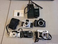 Photo showing 6 cameras and 2 flashes including Nikon, Minolta, Revue, Fujifilm, and Blazetone flash units