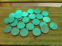 25 Canadian nickels spread out on a wooden surface showing the obverse side with portrait of King George V.