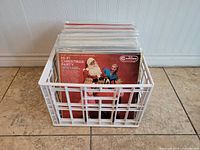 Plastic crate filled with about two dozen Christmas-themed vinyl records in sleeves.