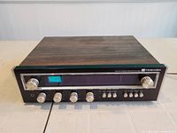 Front view of Toshiba SA-300 stereo receiver showing woodgrain top, black front panel with silver knobs and blue tuning meter illuminated.