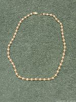Full view of the entire necklace laid flat showing alternating gold and pearl beads arranged in a strand with clasp.