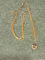 Full view of the 14k gold necklace and pendant laid flat on fabric background