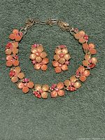 Full view of the Lisner floral necklace and earrings set laid on fabric background.