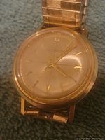 Close-up of Bulova Accutron men's watch face showing gold-tone dial and hands with some wear and scratches on crystal.