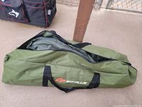 Green GoPlus cloth carry bag for a canopy tent with black handles, partially unzipped showing folded fabric inside.