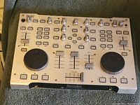Top view of silver Hercules DJ controller showing dual jog wheels, knobs, sliders, and buttons.