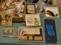 Overview of assorted jewelry, pins, collectible card, and novelty items arranged on towel.