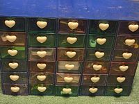 Front view of multi-colored plastic organizer with 25 small drawers each having a white heart-shaped knob