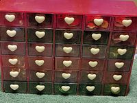 Full view of the red multi-drawer organizer with white heart-shaped handles on each drawer