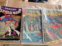 Three Amazing Spider-Man comics (#44, #33, #100) arranged side by side inside protective bags