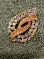 Front view of the signed Coro gold-tone metal brooch with clear and aurora borealis rhinestones, missing one rhinestone.