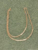 Full view of the sterling silver chain necklace laid flat against a green fabric background for size and condition display.