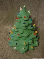 Front view of the green ceramic tree with colored plastic bulb lights inserted. Some bulbs are missing from their slots.