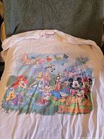 Front of white vintage Disneyland shirt with classic Disney characters and castle graphic.