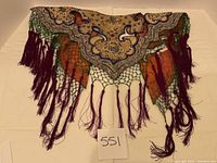 Full view of triangular embroidered collar shawl laid flat showing scalloped edge and hanging tassels