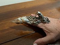 Oblique side view of ring on finger highlighting creature skull and segmented armor plates