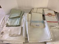 Overview of folded pale green and white damask Irish linen tablecloths and napkins in assorted stacks