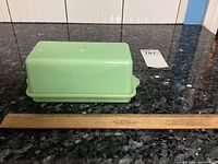 Closed butter dish on countertop with ruler showing length