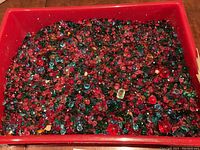 Top view of red tray filled with small faceted glass stones in mixed colors