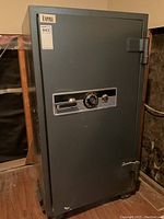 Full view of the large grey Empire fireproof safe standing upright showing the door, handle, hinges, and general exterior condition.