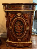 Front view of commode cabinet showing marquetry panel and ormolu mounts.