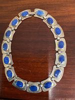 Full view of necklace laid in a circle showing all lapis-inset links.